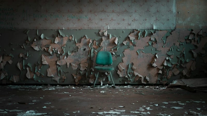 green chair in front of damaged wall